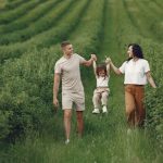 A happy family walking in a lush, green rural field together.